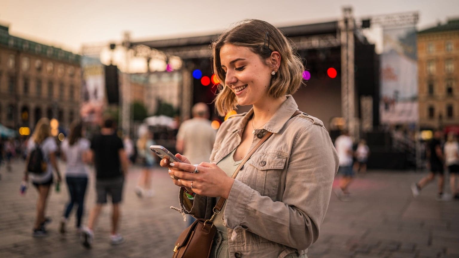 En kvinna tittar på sin telefon framför en scen på Gustav Adolfs torg under Stockholms Kulturfestival en ljummen augustikväll.