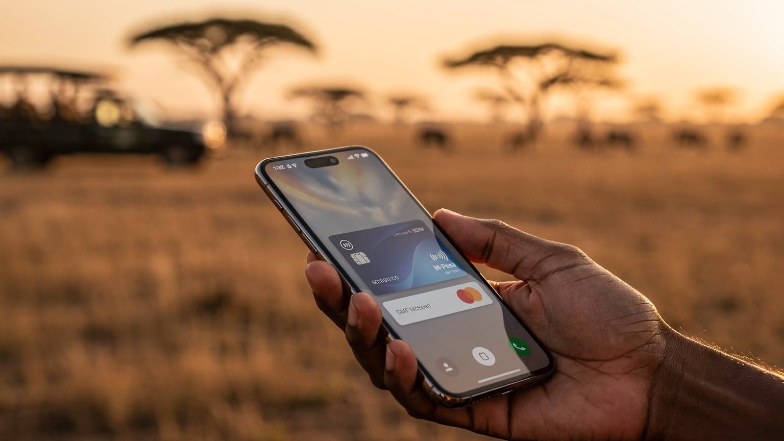 A hand holding a smartphone displaying a generic digital payment or eSIM screen, with a blurred, golden-hour Kenyan safari landscape in the background, symbolizing mobile technology and travel in East Africa.