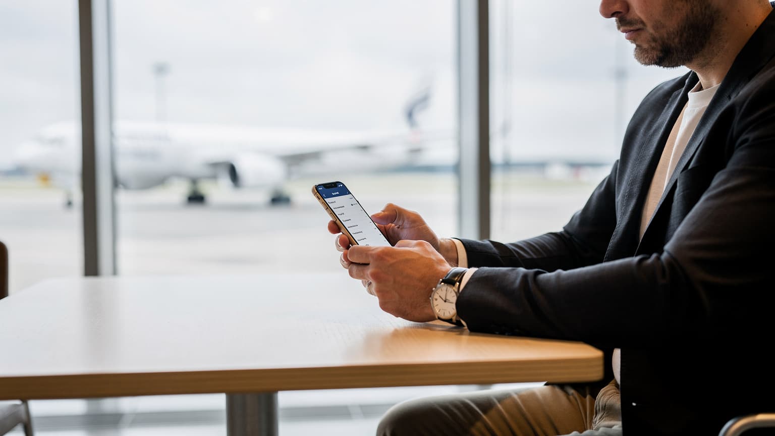 Ein Reisender mit einem Smartphone überprüft am Flughafen Berlin Brandenburg (BER) die eSIM-Einstellungen, während er auf seinen Flug wartet.