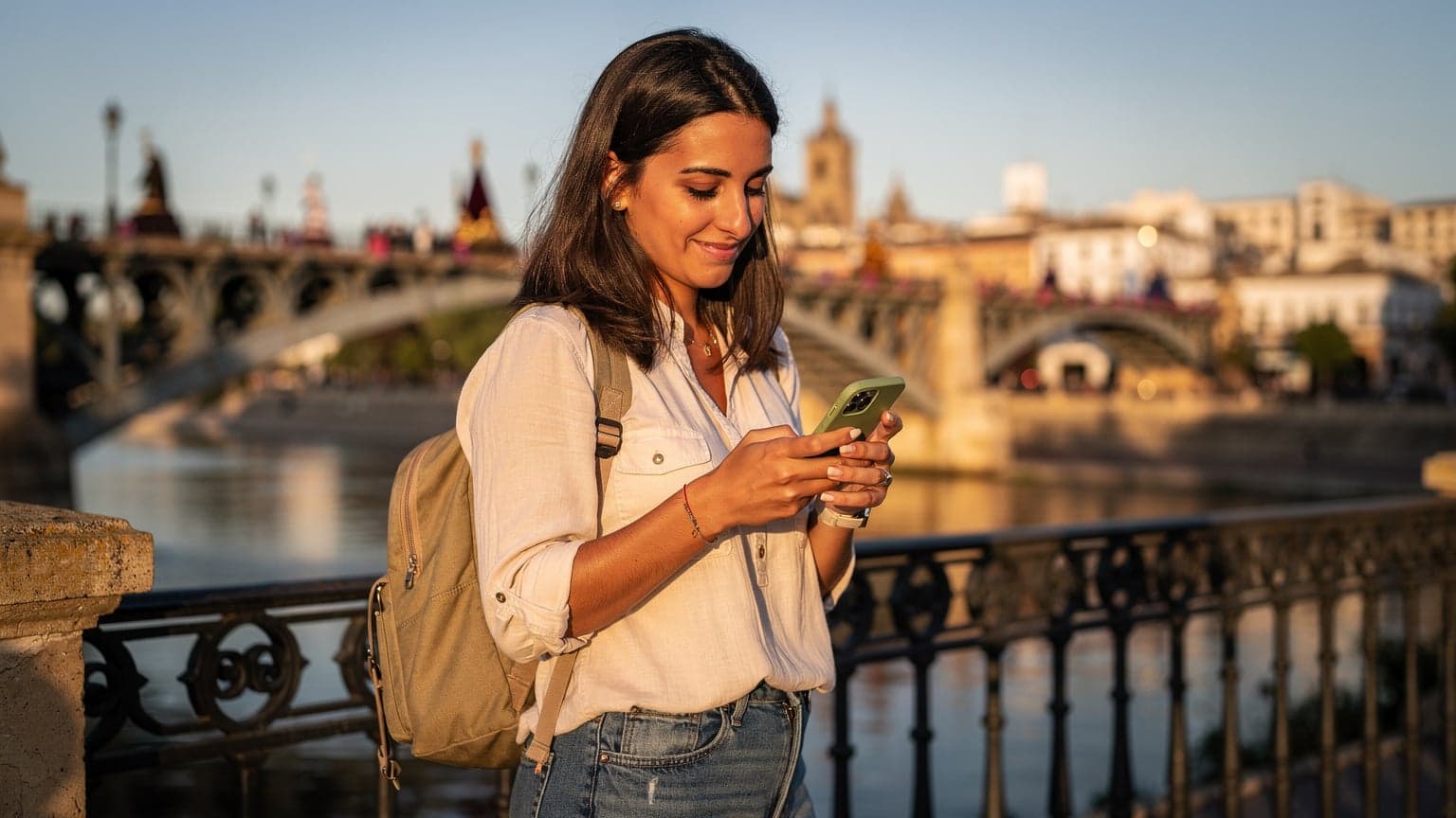 A traveler at Seville's Triana Bridge during Semana Santa 2026, checking their phone for directions with a Cellesim eSIM.