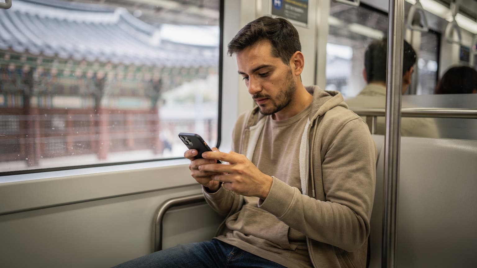 A person navigating a complex transit map on their smartphone, with the bustling Seoul subway platform visible in the background, showing digital nomad life.