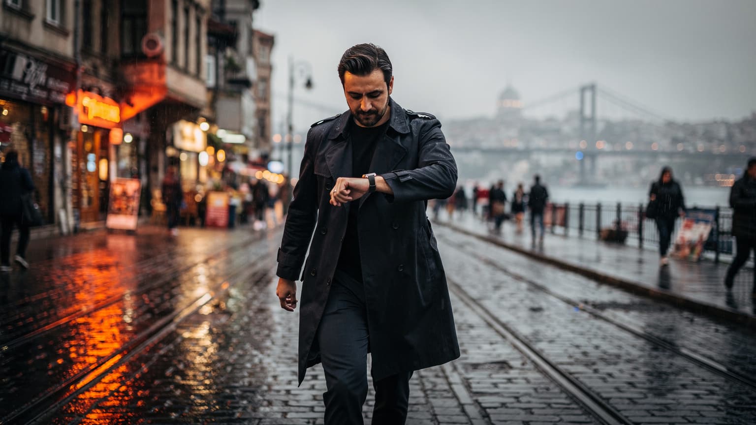 İstanbul Haliç'te yağmurlu bir akşamda, Karaköy tramvay durağı yakınlarında ışıklı dükkanların önünden geçen insanların olduğu, ıslak kaldırımların parladığı bir gece sokak sahnesi.