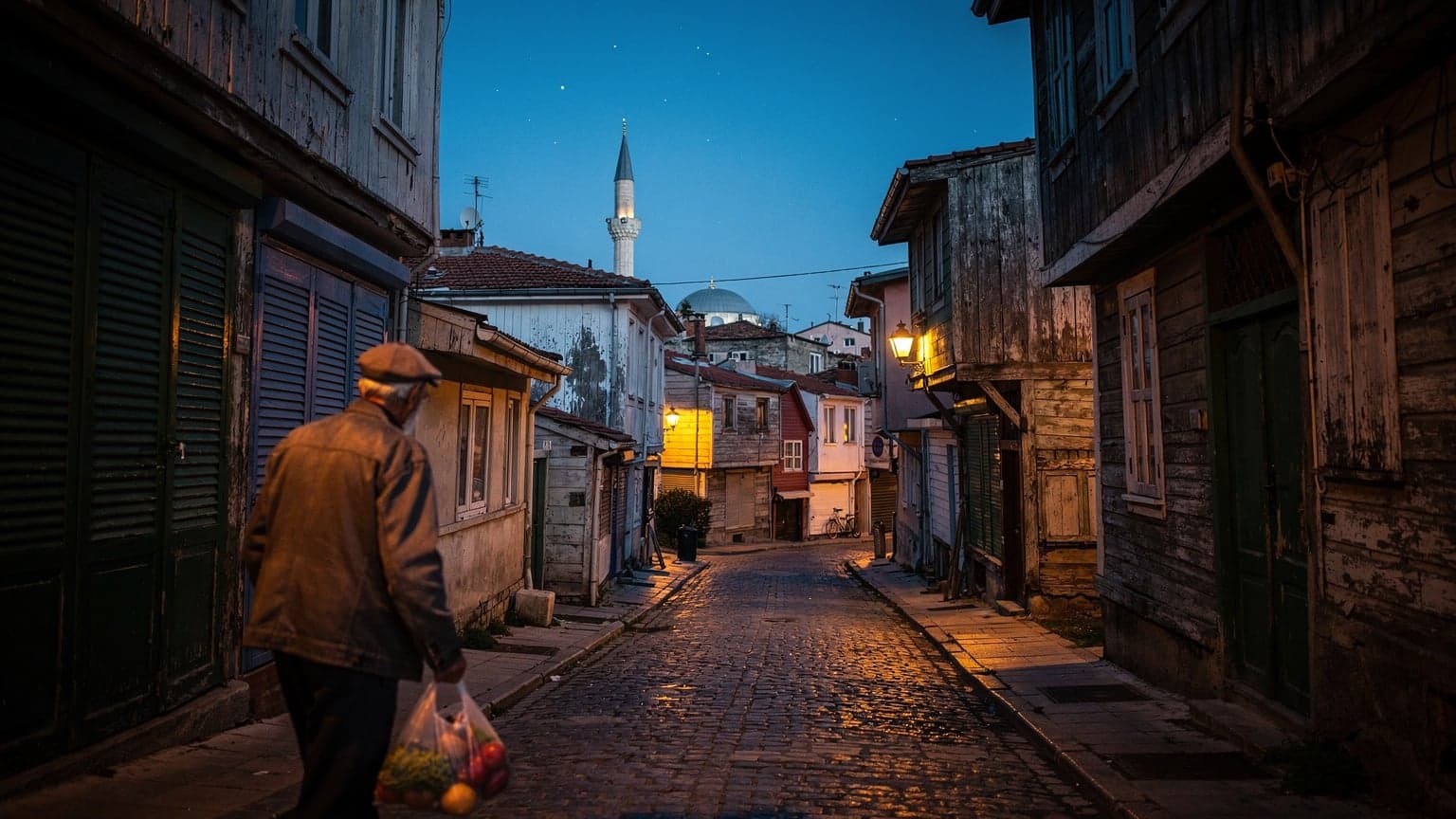 Blå time over en stille gate i Kadıköy, Istanbul, med lukkede skoddører og fjern silhuett av en moské i bakgrunnen.