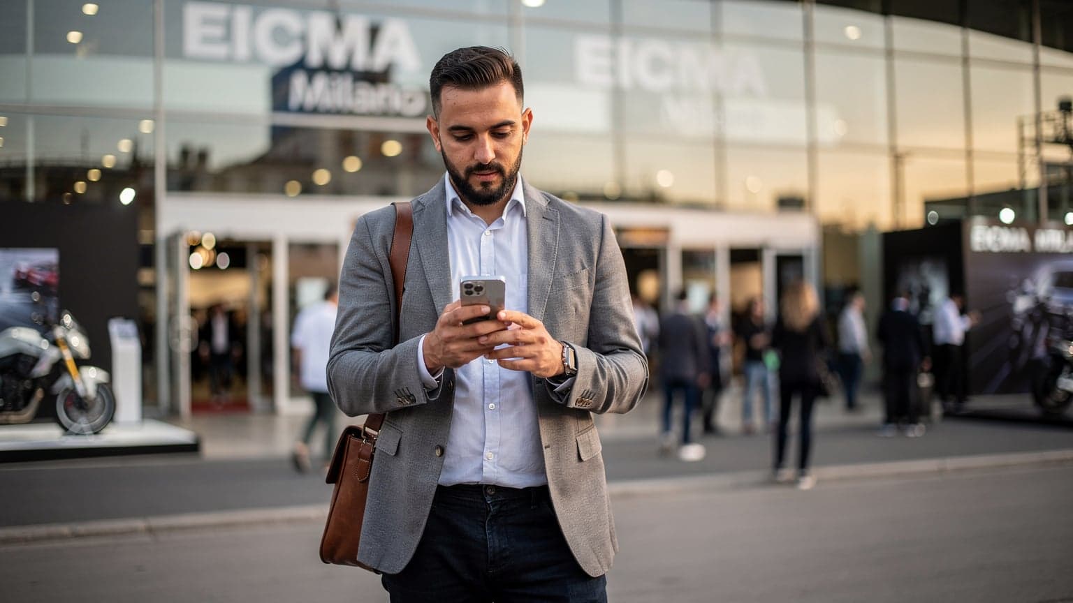 مسافر عربي يستخدم هاتفه الذكي في ميلانو مع خلفية لمعرض EICMA