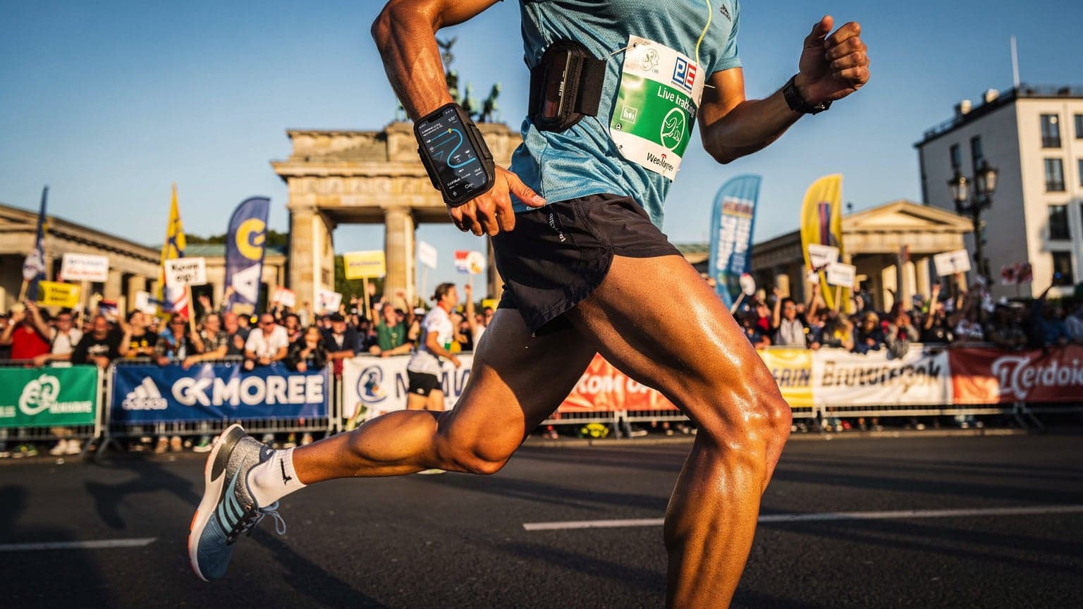 Een marathonloper met een smartphone om zijn pols, die zijn voortgang volgt, met de Brandenburger Tor op de achtergrond in Berlijn.
