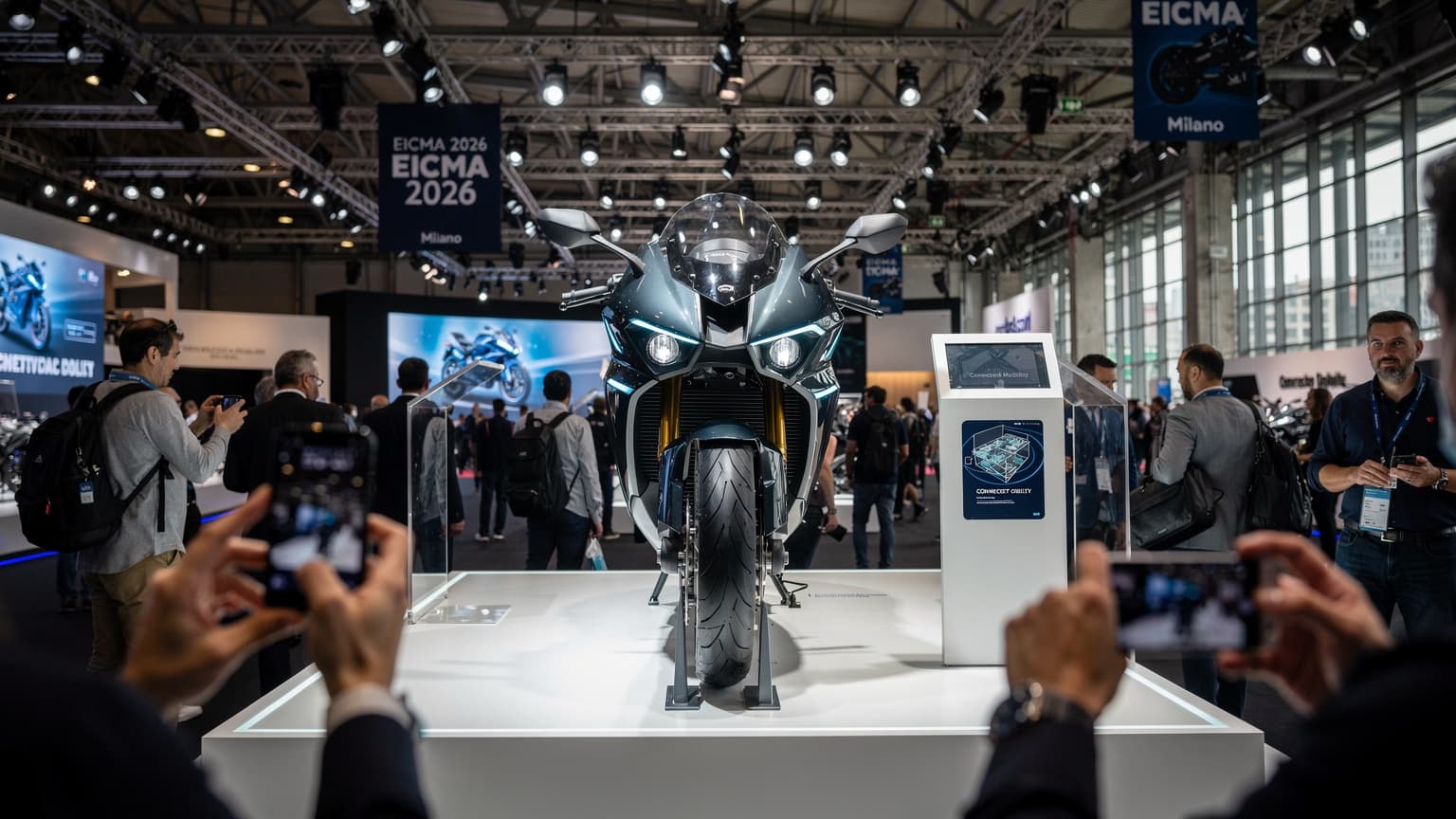 En modern motorcykel utställd på en stor mässa, med besökare i bakgrunden som använder sina telefoner för att navigera och fotografera.