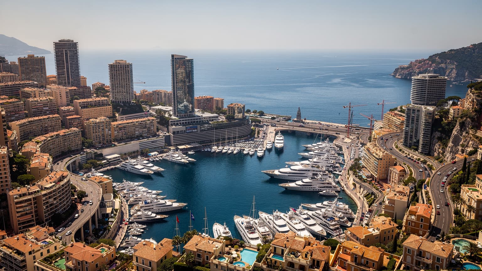 Vista panoramica del Principato di Monaco con edifici moderni e il mare, simbolo di connettività internazionale.