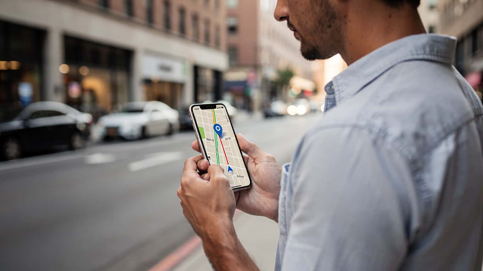 Persona consultando su teléfono móvil en un entorno urbano de Estados Unidos, con un mapa o una aplicación de viaje en la pantalla.