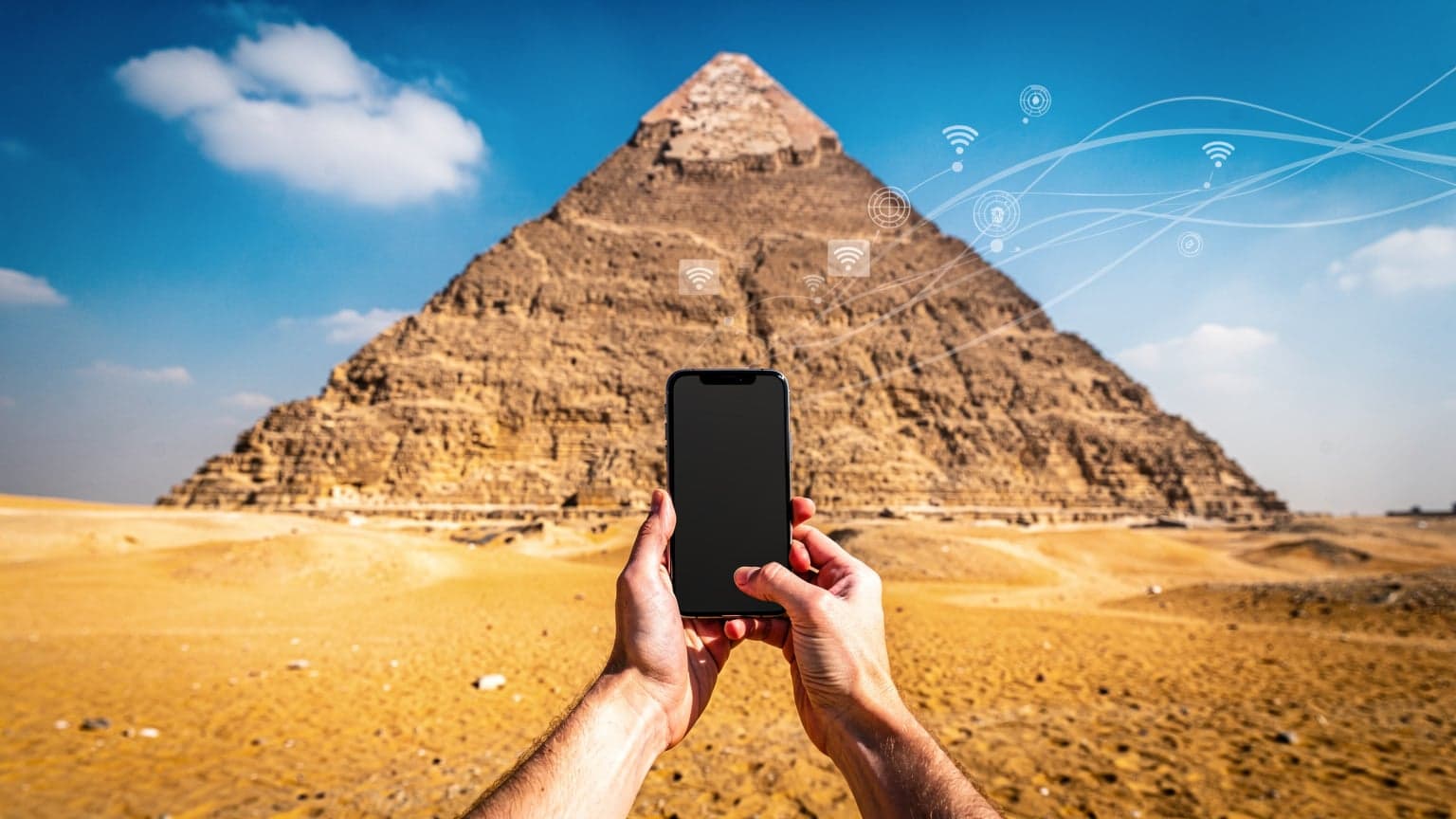 A traveler looking at their phone with the Pyramids of Giza in the background, symbolizing international connectivity in Egypt.