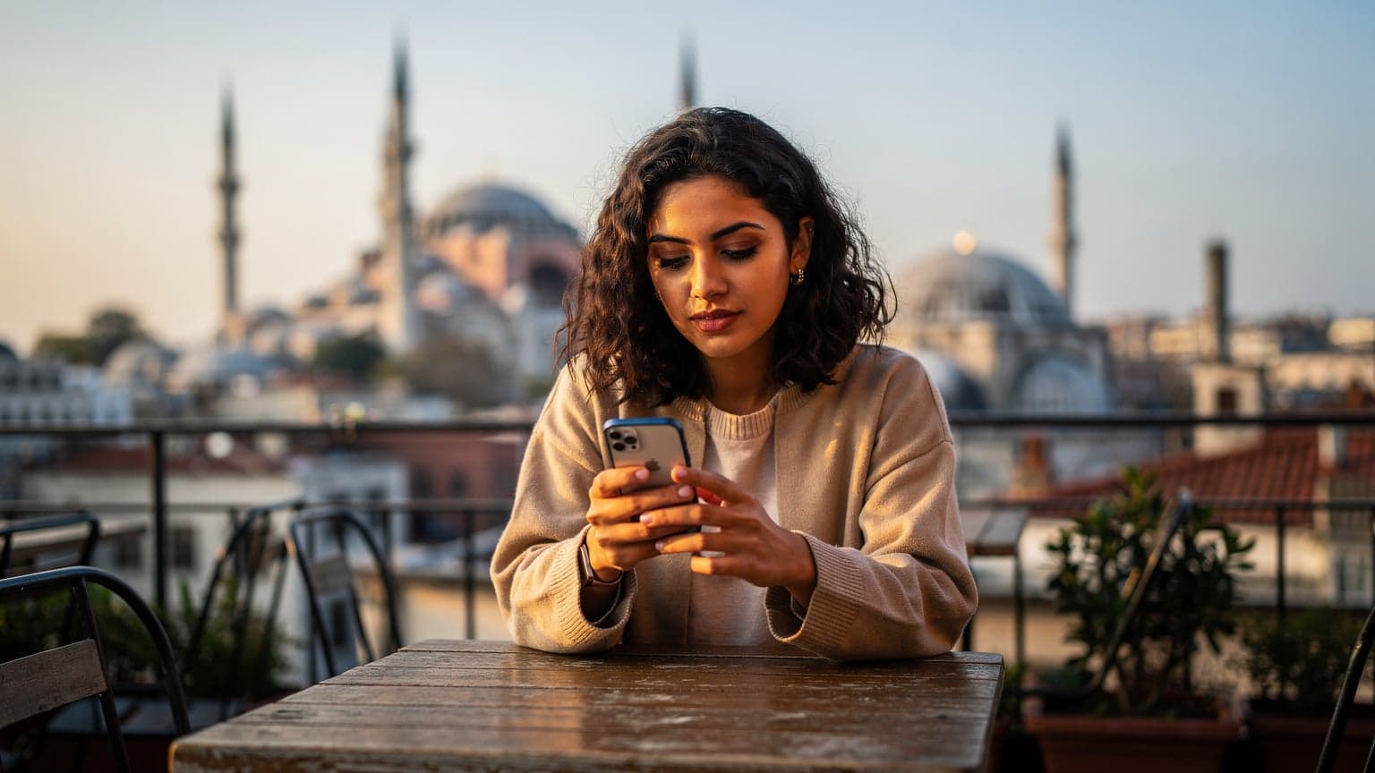 İstanbul'un tarihi yarımadasına bakan bir teras kafede, elinde akıllı telefonunu tutan genç bir kadın, eSIM ayarlarını kontrol ediyor.
