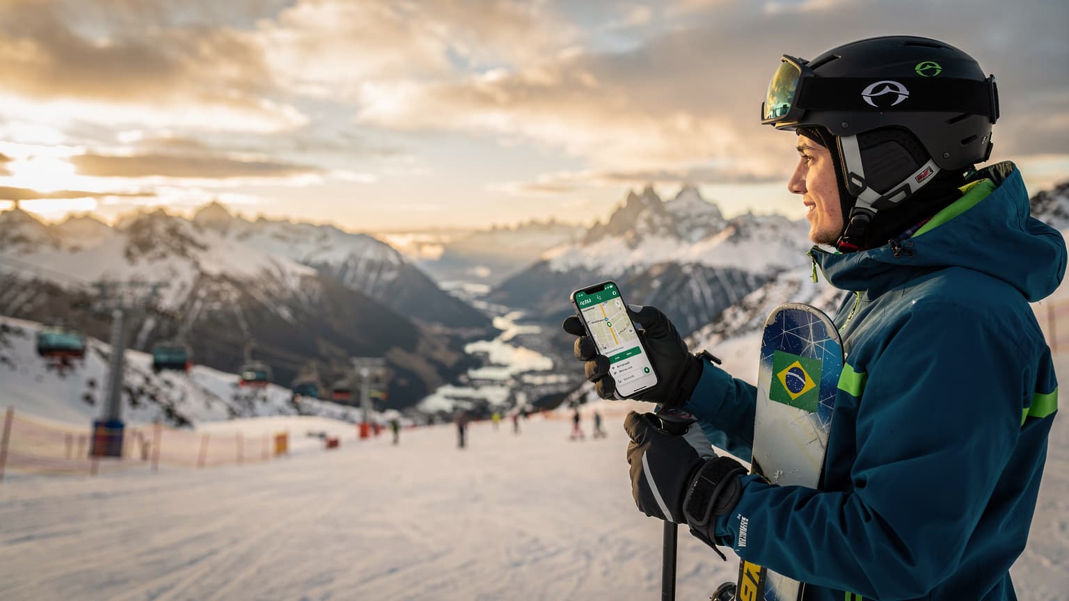Uma mulher sorridente, vestida com roupas de esqui vibrantes e óculos de sol, segura um smartphone enquanto admira a paisagem nevada e majestosa dos Andes chilenos, com picos cobertos de neve e um céu azul claro.
