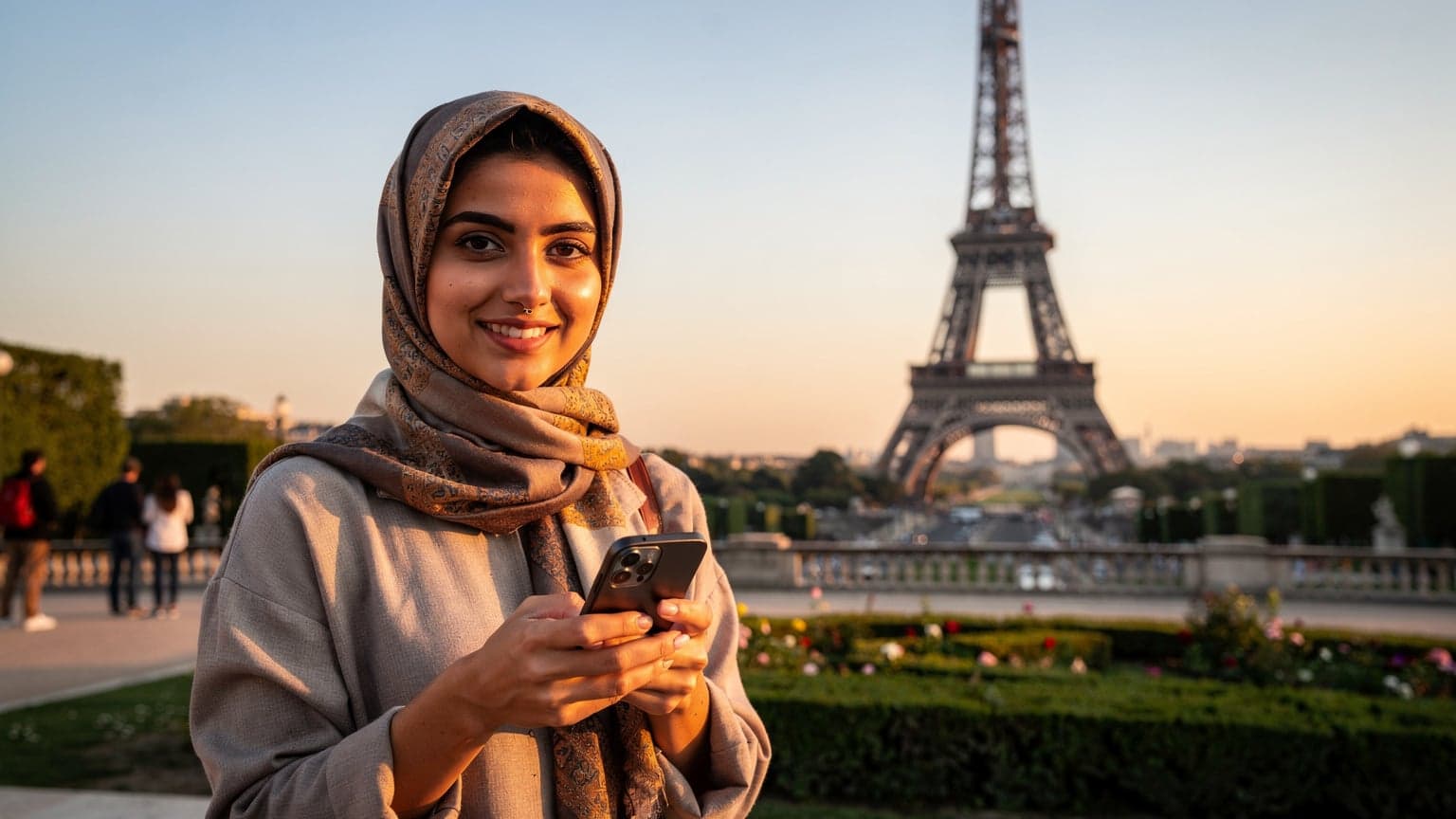 Paris'in iconic Eyfel Kulesi manzarası önünde, genç bir Türk kadın akıllı telefonunda eSIM kurulumunu kontrol ediyor, gülümseyerek kameraya bakıyor.