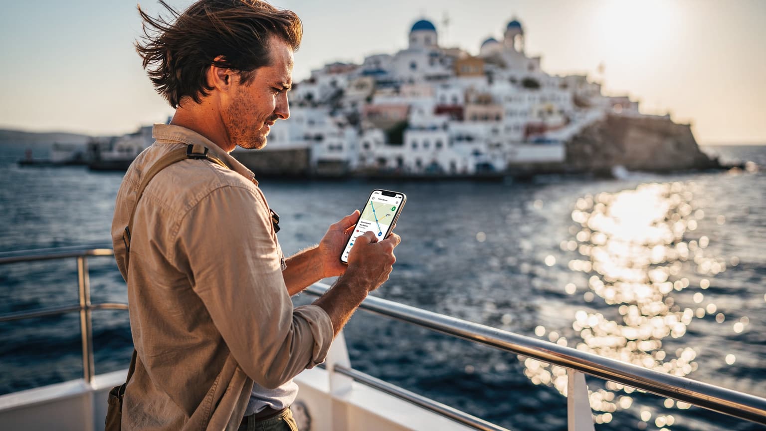 A person on a Greek island ferry uses a smartphone with a white-washed island and blue sea in the background, representing tech-enabled island hopping.