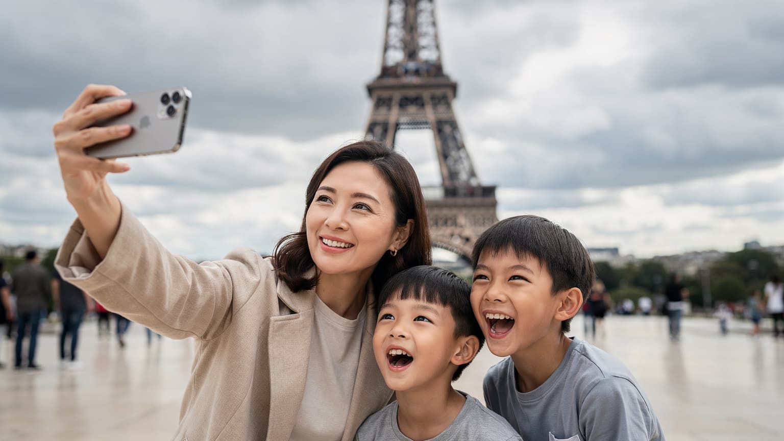 一位中国母亲在法国巴黎埃菲尔铁塔下, 用iPhone 18 Pro手机拍摄家庭合影, 笑容满面, 旁边孩子兴奋地看向镜头。