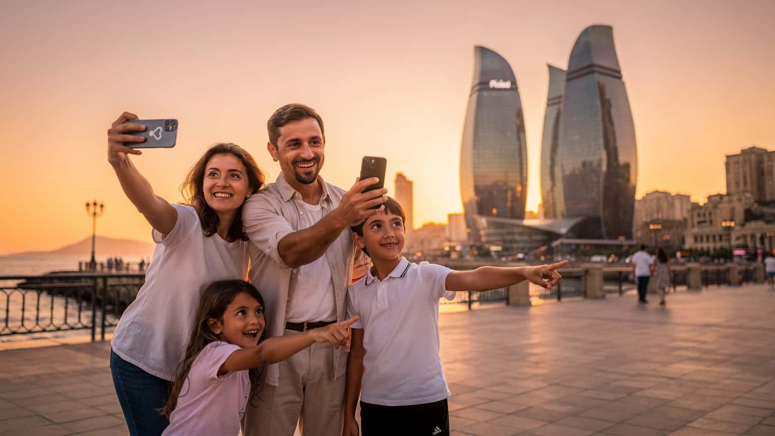 A family, including two children, looking at a smartphone with an eSIM activated while standing in front of the Flame Towers in Baku, Azerbaijan, at sunset.