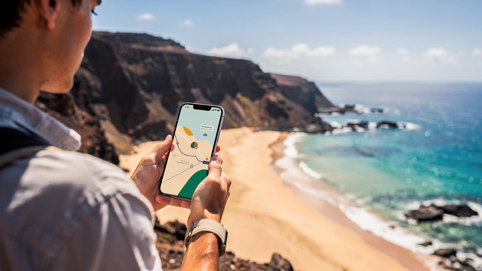 A traveler holding a smartphone, with a beautiful panoramic view of Cape Verde's volcanic mountains, sandy beach, and turquoise ocean in the background under natural sunlight, suggesting global connectivity.