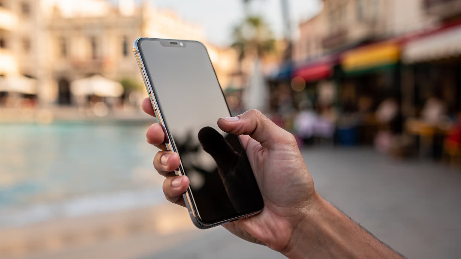 A close-up of a hand holding a modern smartphone against a blurred, sunlit international travel destination, symbolizing seamless global internet connectivity for travelers.
