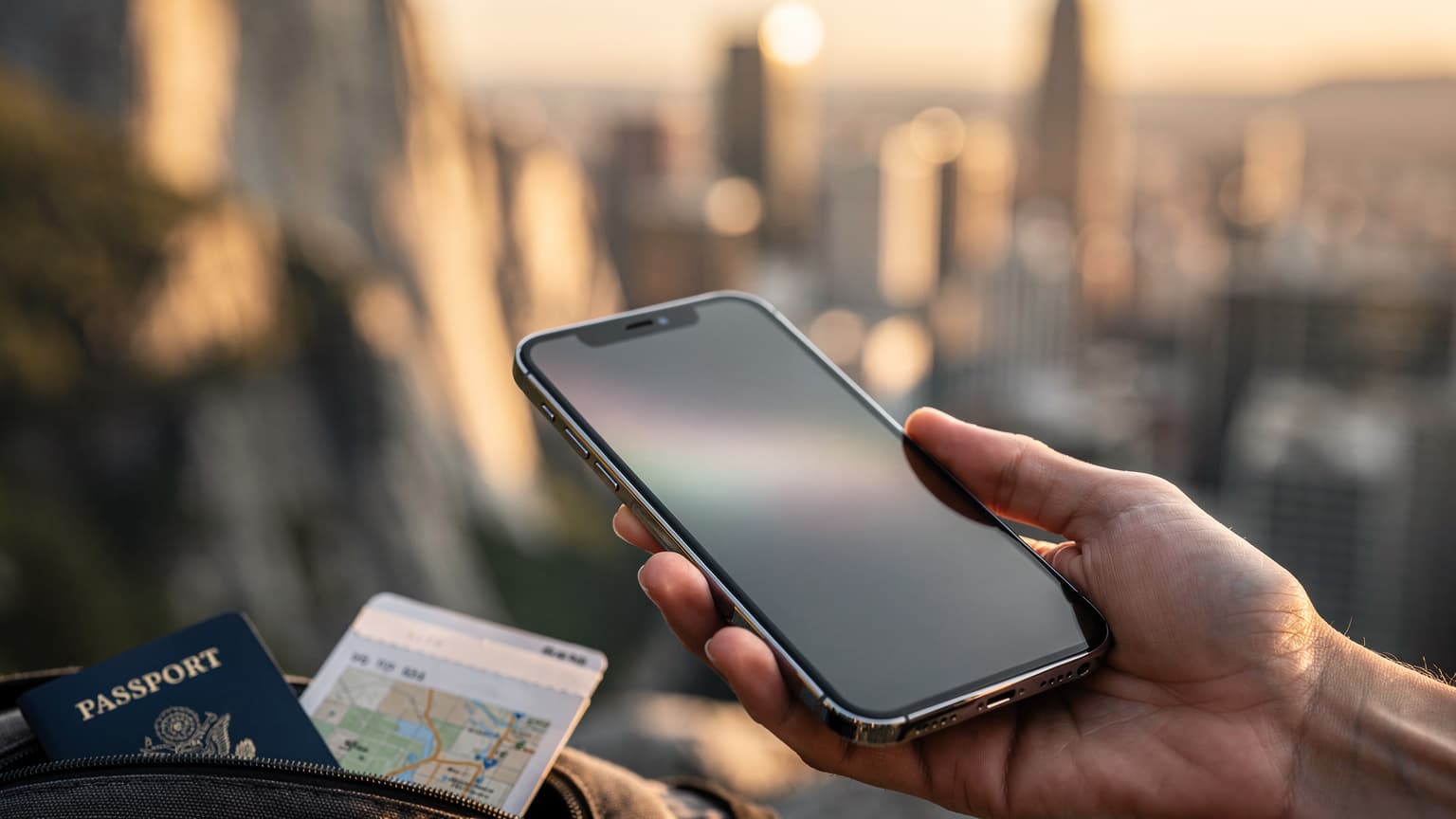 A hand holds a modern smartphone against a blurred background of an iconic American landscape, suggesting seamless travel connectivity.