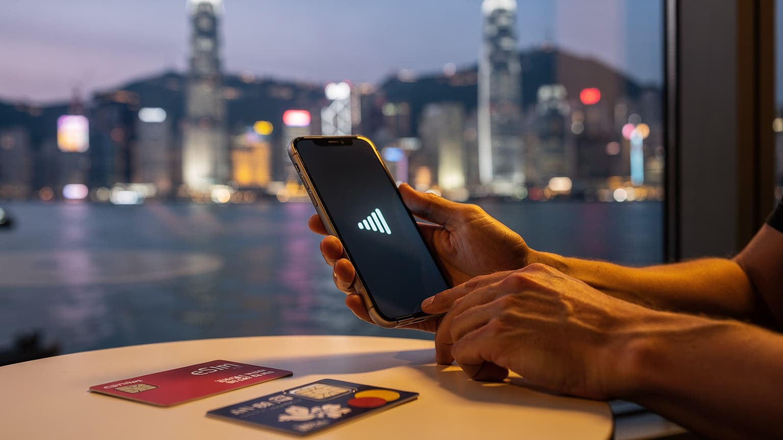 A photorealistic editorial image of a traveler's hands holding a smartphone, with a blurred Hong Kong cityscape in the background. An eSIM card and a local prepaid SIM card are visible on a surface, suggesting choice in mobile connectivity for travel.