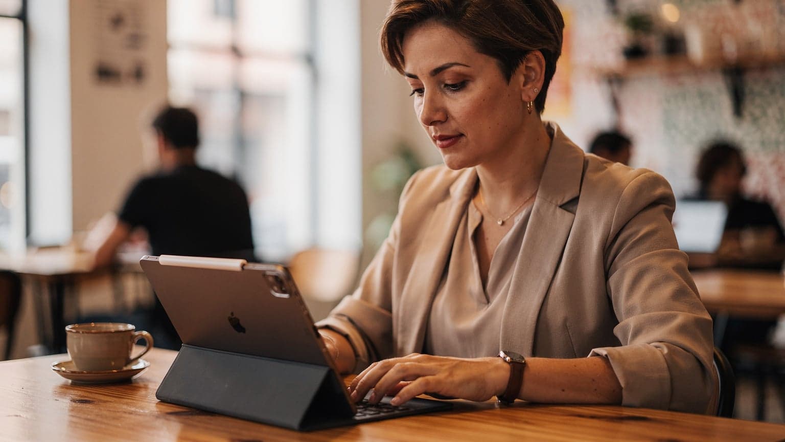 A digital nomad works on her iPad at a communal table in the vibrant Selina co-working space in Palermo Soho, Buenos Aires, with a strong coffee nearby.