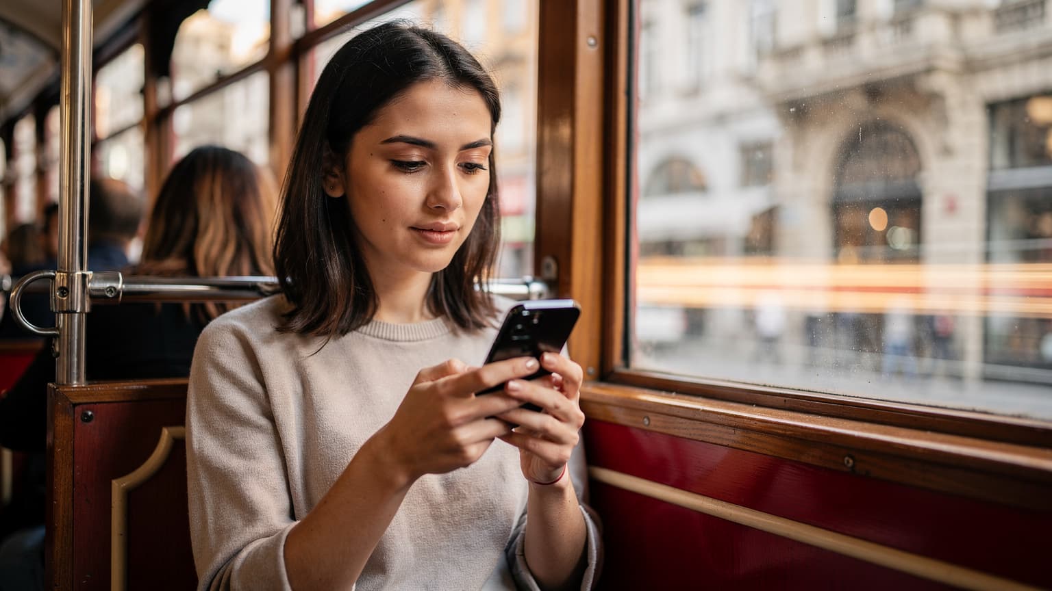 İstanbul'da tarihi bir tramvayda oturan, akıllı telefonunda eSIM kurulum adımlarını kontrol eden genç bir kadın.