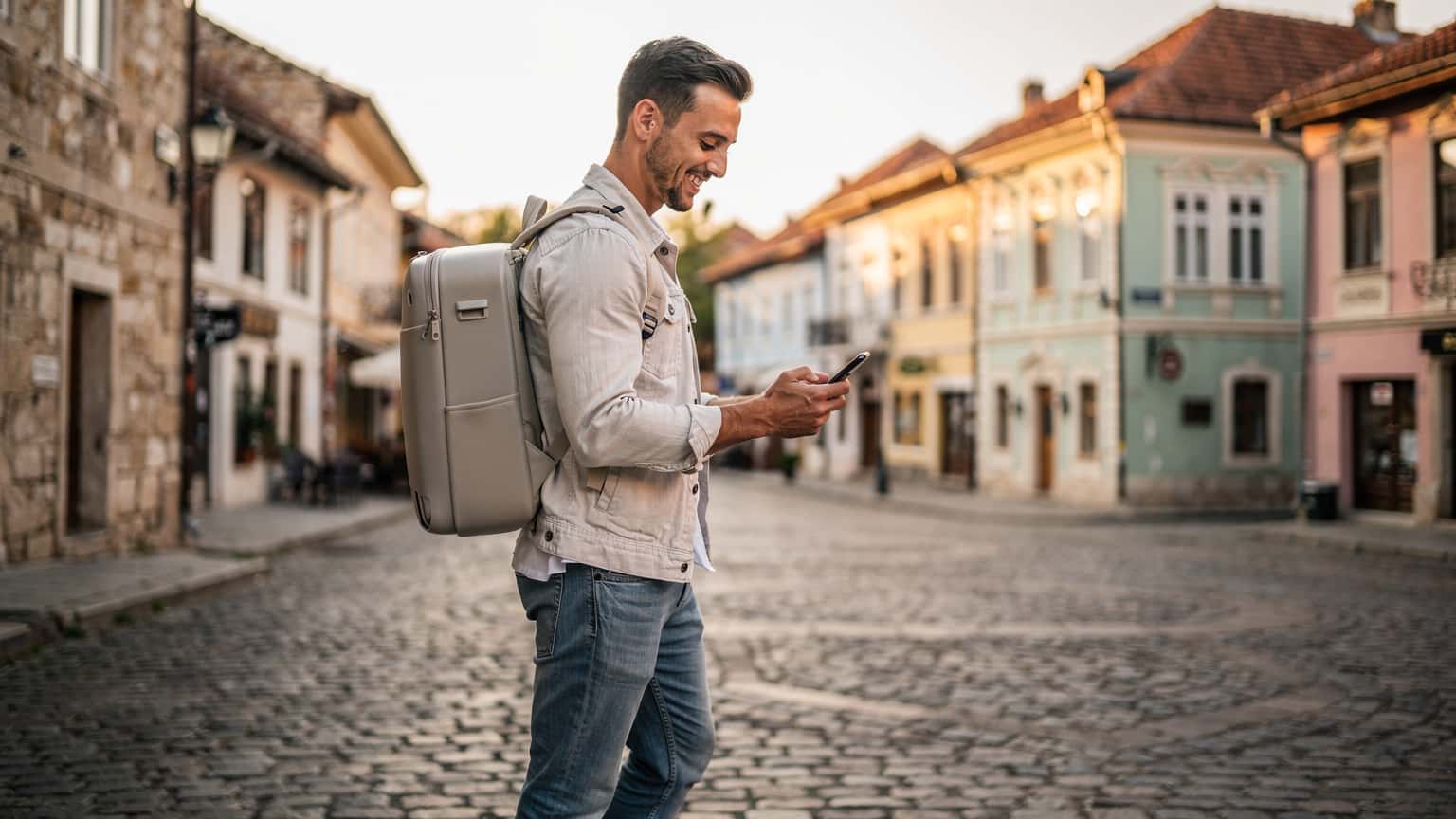 A young traveler uses a smartphone in a sunny European city square, conveying easy connectivity during travel.