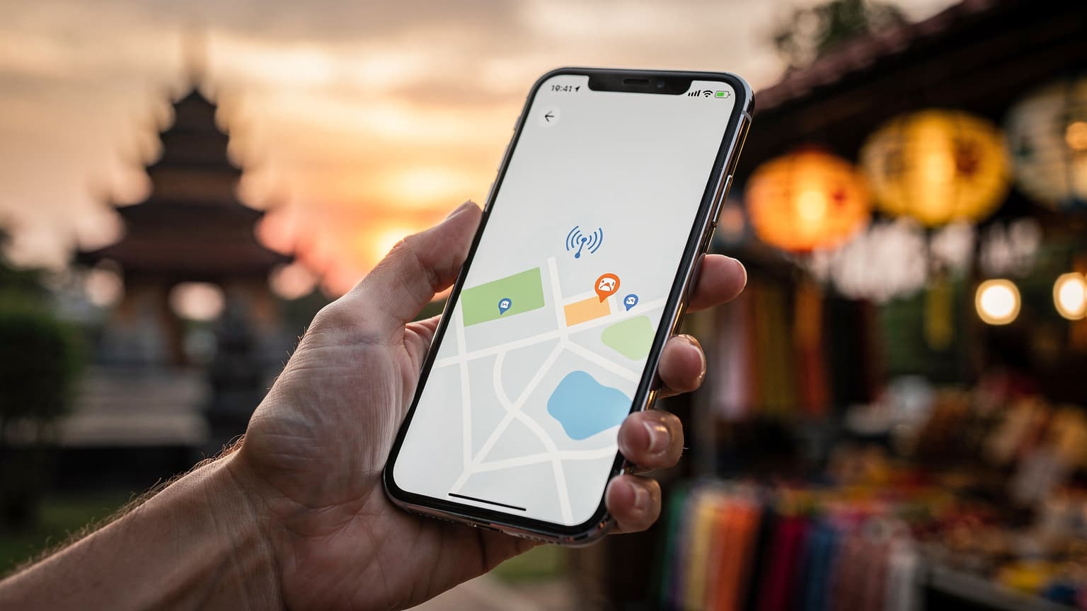 A hand holding a smartphone against a blurred, warm-lit Southeast Asian backdrop, representing travel connectivity and eSIM choices.