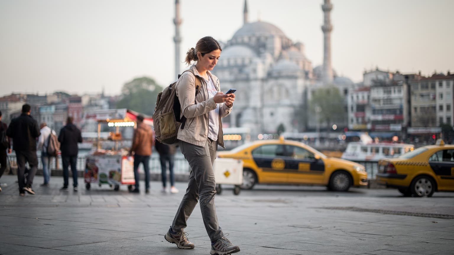 İstanbul'un hareketli Eminönü Meydanı'nda, Yeni Cami önünde elinde akıllı telefonuyla yol tarifi bakan genç bir kadın.