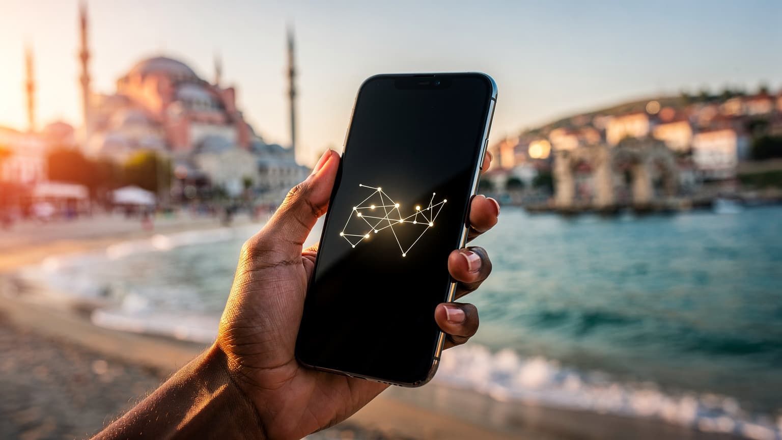 A hand holds a smartphone with a blurred background showing Istanbul's skyline on one side and a sunny Turkish coast on the other, symbolizing modern travel and connectivity.