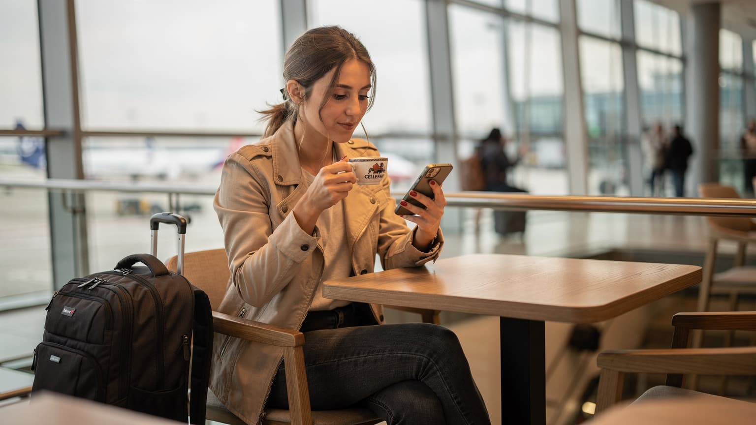 İstanbul Havalimanı dış hatlar terminalinde, bir dijital nomad kahvesini yudumlarken akıllı telefonundan Cellesim eSIM profilini kontrol ediyor.
