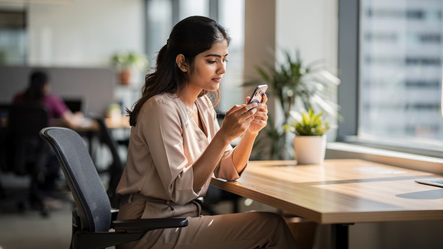एक महिला बैंकॉक के 'द वर्कशॉप' को-वर्किंग स्पेस में अपने iPhone पर eSIM एक्टिवेट कर रही है, उसके लैपटॉप पर कुछ कोड दिख रहे हैं.